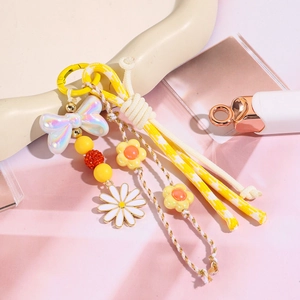 Détail de porte-clés perlé avec nœud jaune, fleurs de marguerite et cordon tressé coloré