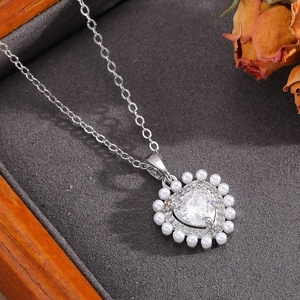 Dettaglio del ciondolo a forma di cuore con zircone, perle bianche e cristalli brillanti