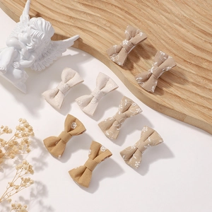 Detailed set of 8 cotton bow hair clips with white floral embroidery in earth tones