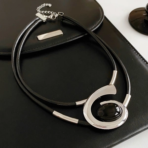 Detail of vintage double-layer necklace with silver spiral pendant and black oval gem