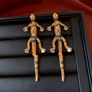 Dettaglio degli orecchini a forma di lucertola vintage con strass arancio e verdi