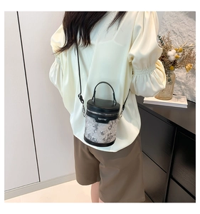 Detail showing embroidered floral cylinder bucket bag with silver fabric and black trim