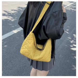 Yellow quilted corduroy tote bag with diamond stitching shown in a stylish crossbody wear