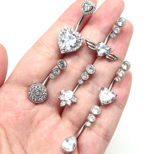 Close-up of 6 silver navel rings with heart and teardrop cubic zirconia held by hand