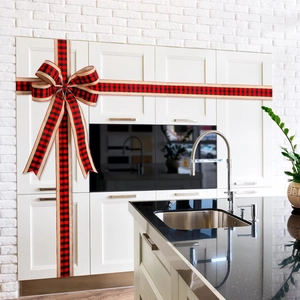 Detail einer rot-schwarz karierten Weihnachtsschleife an einer weißen Küchentür
