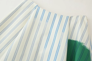 Detail shot of blue and white striped cotton-linen fabric with green patchwork accent