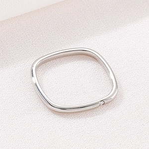 Macro shot of silver square ring with polished finish and a single corner diamond accent