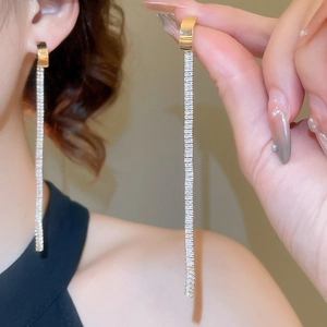Close-up of elegant gold linear earrings with rectangular cubic zirconia on a model