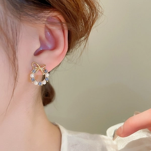Close-up of bow knot wreath earring with pearls and blue crystals on a female model