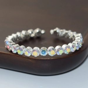 Detail of silver open bangle featuring sparkling AB rhinestones on a wooden stand