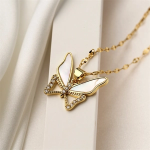 Macro shot of a golden butterfly pendant with white shell wings and sparkling cubic zirconia