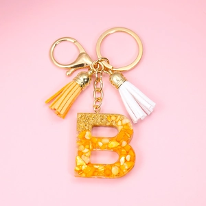 Resin initial B keychain with orange gold foil flakes and colorful suede tassels