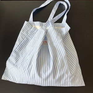Dettaglio della borsa in cotone a righe blu con etichetta Bébé su fondo legno