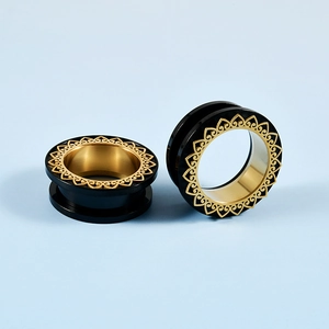 Nahaufnahme von schwarz-goldenen Lotusblüten-Ohr-Tunnels für gedehnte Ohrläppchen-Piercings