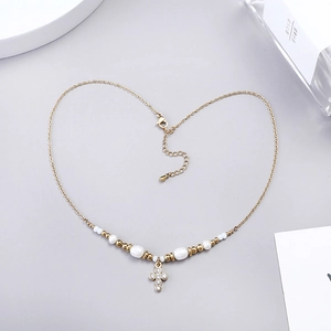 Macro shot of gold-plated cross necklace with pearls and rhinestones in heart shape