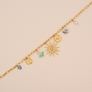 Dettaglio di un bracciale dorato con ciondoli a forma di sole, trifoglio, cuore e perle