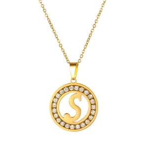 Detail of golden circular hollow pendant featuring letter S with sparkling crystals