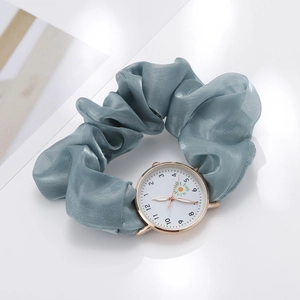 Macro shot of grey-blue fabric scrunchie strap watch with daisy motif on white dial
