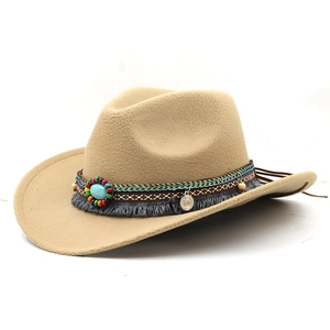 Detail of ethnic ribbon decoration with turquoise stone and tassel on beige felt cowboy hat