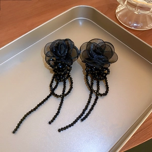 Vue macro de boucles d'oreilles rose en organza noir avec glands en perles facettées