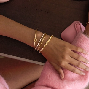 Detailed view of 18K gold stainless steel knotted bangle and layered bracelets on wrist
