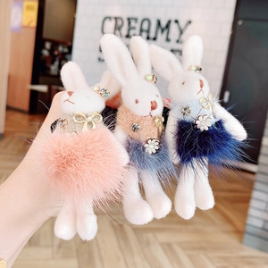 Detailed view of plush rabbit charms in pink, khaki, and blue with rhinestone bow accents