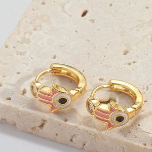 Detail of gold Hamsa Hand and Evil Eye earring with pink enamel and zircons