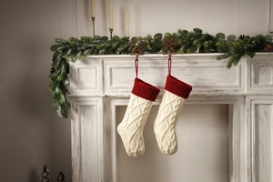 Detail of red and white knitted Christmas stockings with cable pattern on fireplace mantel