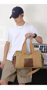 Man carrying khaki canvas and brown leather travel bag in a modern home setting