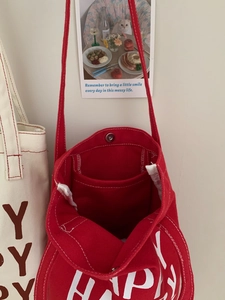 Detail of red canvas tote bag showing magnetic snap closure and internal pocket