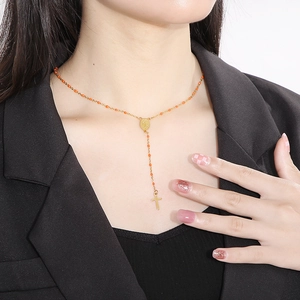 Gold Y-shaped necklace with orange beads, religious icon medal and cross pendant