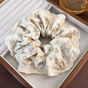 Close-up of beige floral fabric scrunchie with lace trim in a wooden jewelry box