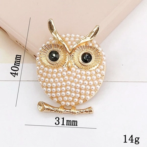 Golden owl brooch with pearls and rhinestones measuring 40mm by 31mm on white background