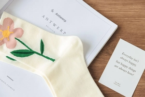 Detailed close-up of beige mid-calf socks featuring pink floral and leaf embroidery