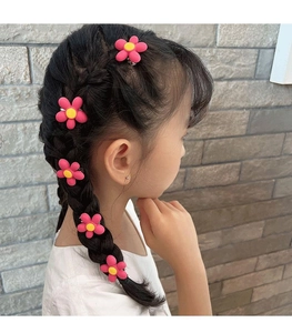 Detail von rosa Blumen-Haarspangen mit mattem Finish an einer geflochtenen Kinderfrisur