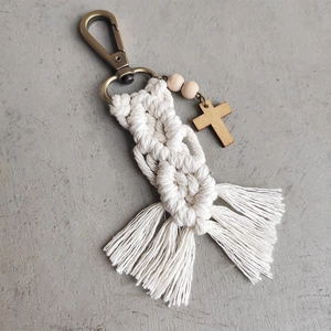 Detailed macro view of handmade woven cotton rope keychain with wooden beads and cross charm