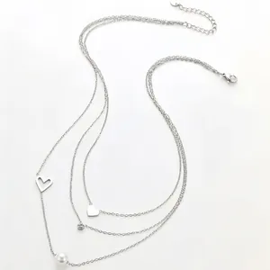Detailed view of triple-layered 18k gold stainless steel necklace with pearl and hearts