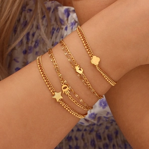 Five-piece gold stainless steel layered bracelet set with star and heart charms on wrist