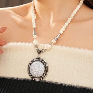 Detail of bohemian necklace featuring white faux turquoise stone and silver vintage carvings
