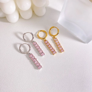 Macro detail of gold and silver steel hoop earrings with hanging pink oval zircon stones