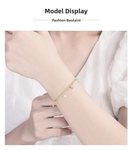 Detail view of a layered gold clover bracelet on a female model with a stylish knit top