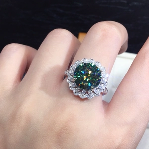 Close-up of luxury silver ring with green moissanite stone and sparkling double halo