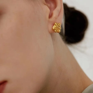 Golden irregular lava texture stud earrings with crinkled metallic design on model