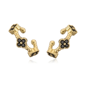 Macro detail of gold C-shaped ear cuffs featuring black clover motifs and beaded edges
