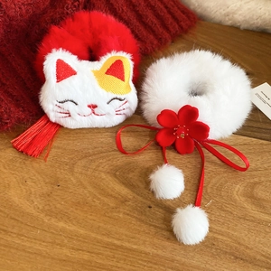 Macro shot of winter plush lucky cat hair scrunchies with tassels and floral details
