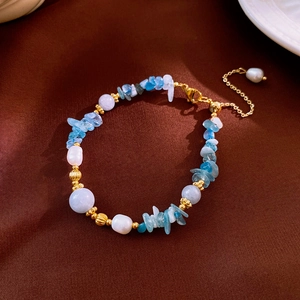 Detail view of pearl and blue aquamarine beaded bracelet on brown silk background
