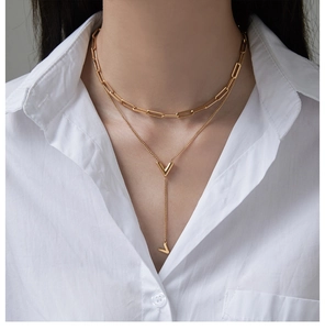 Detailed view of layered 18K gold plated necklaces with iconic V pendant on a model