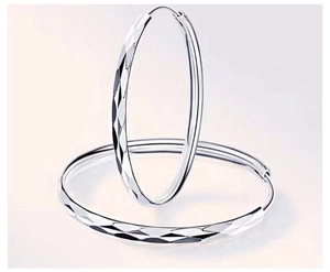 Detail view of large silver hoop earrings featuring a brilliant diamond-cut textured finish