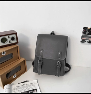 Detail of grey PU leather backpack featuring retro double buckle straps and flap closure