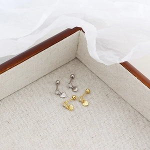 Close-up of gold and silver heart stud earrings with sparkling zircon in a jewelry box